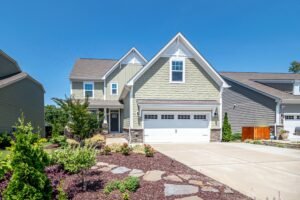 Awesome House (Sample) Charming suburban house with green facade, garage, and landscaped yard on a clear day.